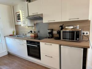 a kitchen with white cabinets and a microwave at Côté Criée sur le port de pêche in Granville +9 photos
