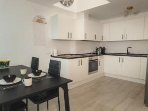 a kitchen with white cabinets and a black table at New - MiJa basement Loft Apartment steps from Beach - perfect for Sun and Sport Seekers in Marbella