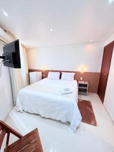 a bedroom with a large white bed and a flat screen tv at Vila do Morro Pousada in Morro de São Paulo