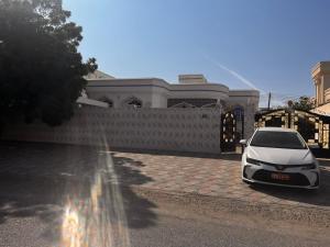 een witte auto geparkeerd voor een gebouw bij Amour Hostel in Seeb