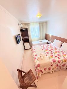 a bedroom with a large bed and a chair at Vila do Morro Pousada in Morro de São Paulo