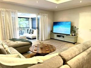 a living room with two couches and a flat screen tv at Beach Road Bliss- Whitsundays in Cannonvale