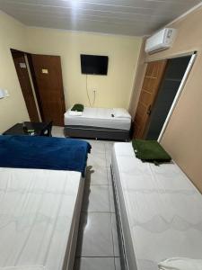 two beds in a room with a tv and a bed at POUSADA DEUS É FIEL Coruripe in Coruripe