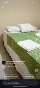 a poster of a bed with green sheets and pillows at POUSADA DEUS É FIEL Coruripe in Coruripe