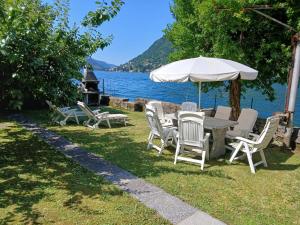 a table with chairs and an umbrella next to a lake at La casa di Mimo in Nesso