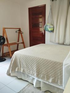 a bedroom with a white bed and a chair at Casa Mari Suites in Canoa Quebrada