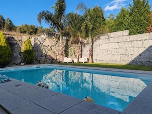 a swimming pool in front of a stone wall at Vila do Sol in Figueiredo