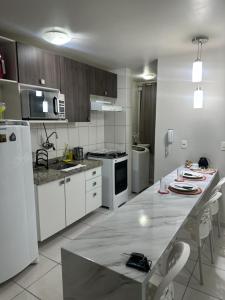 Edf Monte Valpine في ماسيو: مطبخ مع أجهزة بيضاء وطاولة مع كراسي