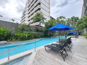 een paar stoelen en een parasol naast een zwembad bij Marvest Lover in Ban Nong Chaeng