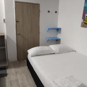 una piccola camera con letto e porta in legno di Hostal Paloma Café a Palomino