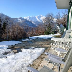 een terras met een tafel en stoelen en sneeuw bij Trekker's Home L'infinito & SPA in Pessinetto
