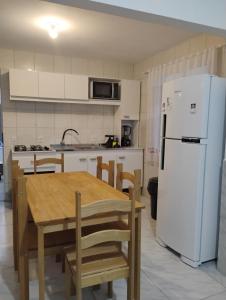 a kitchen with a table and a white refrigerator at Aconchego Maria Laura in Palhoça