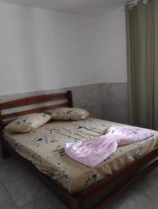 a bed with pillows and a blanket on it at Aconchego Maria Laura in Palhoça