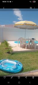a dog sitting next to a table and an umbrella at Casa temporada aracaju sergipe in Aracaju