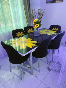 einen Esstisch mit schwarzen Stühlen und Blumen darauf in der Unterkunft Somerset Apartmento in Tokuse