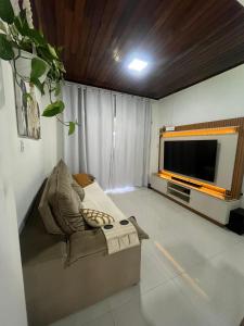 a living room with a couch and a flat screen tv at Casa de Temporada, 2 Quartos com Ar - Prado BA in Prado