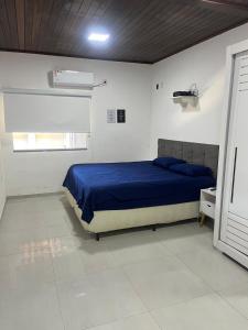 a bedroom with a blue bed in a white room at Casa de Temporada, 2 Quartos com Ar - Prado BA in Prado