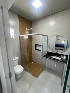 a bathroom with a toilet and a sink and a mirror at Casa de Temporada, 2 Quartos com Ar - Prado BA in Prado