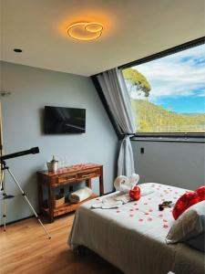 a bedroom with a bed and a large window at Recanto do Tabuleiro chalé com hidro, lareira, churrasqueira e cozinha perto de floripa in Aguas Mornas