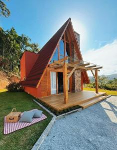 a small house with a large wooden deck at Recanto do Tabuleiro chalé com hidro, lareira, churrasqueira e cozinha perto de floripa in Aguas Mornas