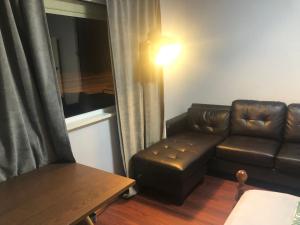 a living room with a leather couch and a table at Airport Master Room in Perth +3 photos