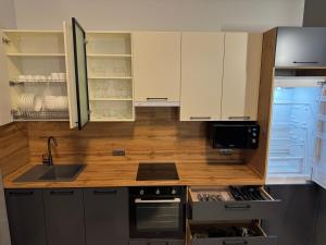 a kitchen with white cabinets and an open refrigerator at cottages GRUN in Yablunytsya