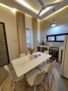 een keuken en eetkamer met een witte tafel en stoelen bij Sinkhole Chalet in Bimmah