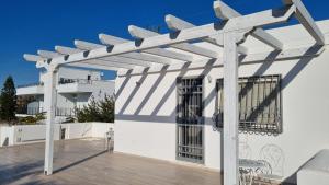 een witte pergola aan de zijkant van een wit gebouw bij Elements Rooms in Porto Cesareo