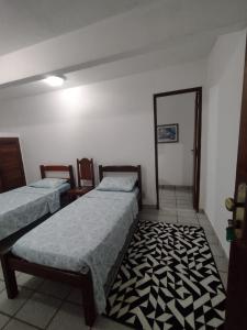 een kamer met 2 bedden en een tapijt bij Pousada do Nilo in Itapemirim
