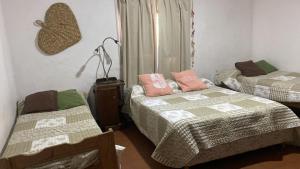 una camera con 2 letti e una lampada a muro di Hosteria Calamuchita a Villa del Dique