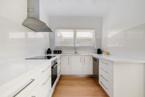 a white kitchen with white counters and white cabinets at The Ocean Gem at Rosebud with its own Private Beach Box in Rosebud