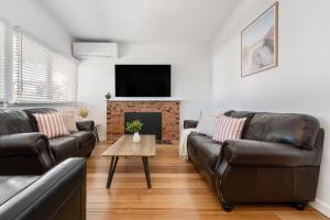 a living room with two leather couches and a fireplace at The Ocean Gem at Rosebud with its own Private Beach Box in Rosebud