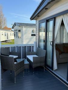een terras met stoelen en een tafel en een bank bij Bishops Beach Stays in Walton-on-the-Naze