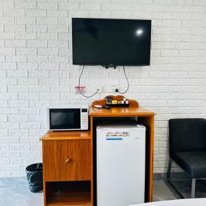 a tv on a table with a refrigerator and a microwave at Aussie Rest Motel in Cessnock