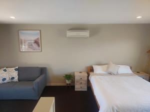 a bedroom with a bed and a couch at Mapua Hills Hideaway in Upper Moutere