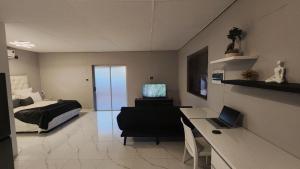 a bedroom with a bed and a desk with a laptop at Pine Self-Catering Unit in Windhoek