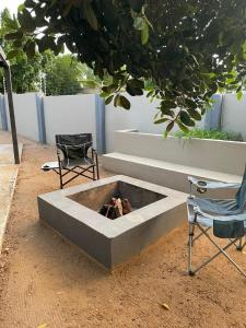 a concrete fire pit with two chairs and a tree at Pine Self-Catering Unit in Windhoek