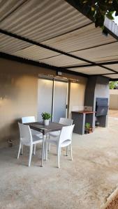 a table and white chairs under awning at Pine Self-Catering Unit in Windhoek