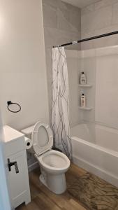 a white bathroom with a toilet and a bath tub at Elian's Nest in Saskatoon