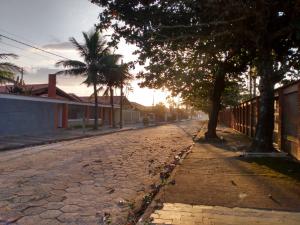 an empty street with palm trees and a fence at Casa Duque Peruíbe in Peruíbe