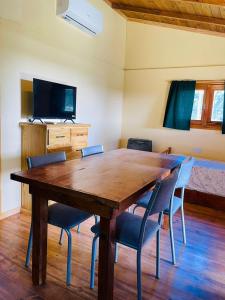 a dining room table with chairs and a television at Cabaña 4 in Necochea +2 photos