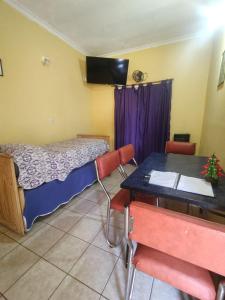 a room with a bed and a desk with a table and chairs at Deptos Peumayen Familiar - Parking - Excelente Ubicacion - Full Equipado in Río Colorado
