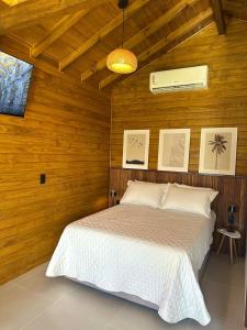 a bedroom with a bed in a wooden wall at Cabana Raiz & Mar - 01 in Imbituba