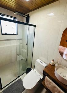 a bathroom with a toilet and a glass shower at Cabana Raiz & Mar - 01 in Imbituba +2 photos
