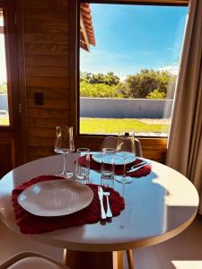 a white table with wine glasses and a window at Cabana Raiz & Mar - 01 in Imbituba