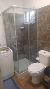 ein Badezimmer mit Toilette und Glasdusche in der Unterkunft Chalet Bilu in Piriápolis