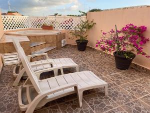 a patio with two chairs and a table and flowers at Condo Riviera in Puerto Aventuras