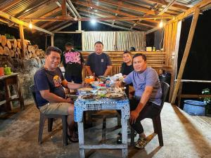 a group of men sitting around a table with food at SIRUS Resort Tagulandang in Kisihang +36 photos