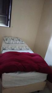 a bed with a red and white blanket on it at Recanto Dunas Santa Rita in Estância +1 photo