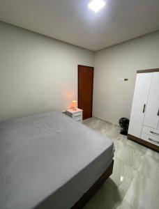 a white bedroom with a bed and a night stand at Ap Seabra 2 quartos in Seabra